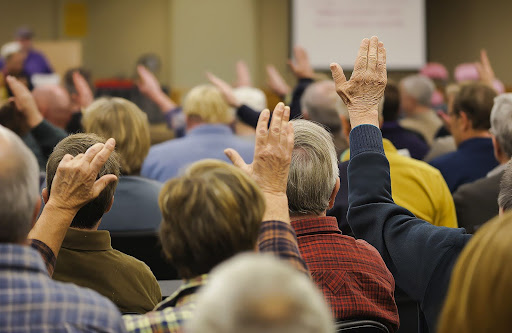 people raising hands | proxy voting in HOA
